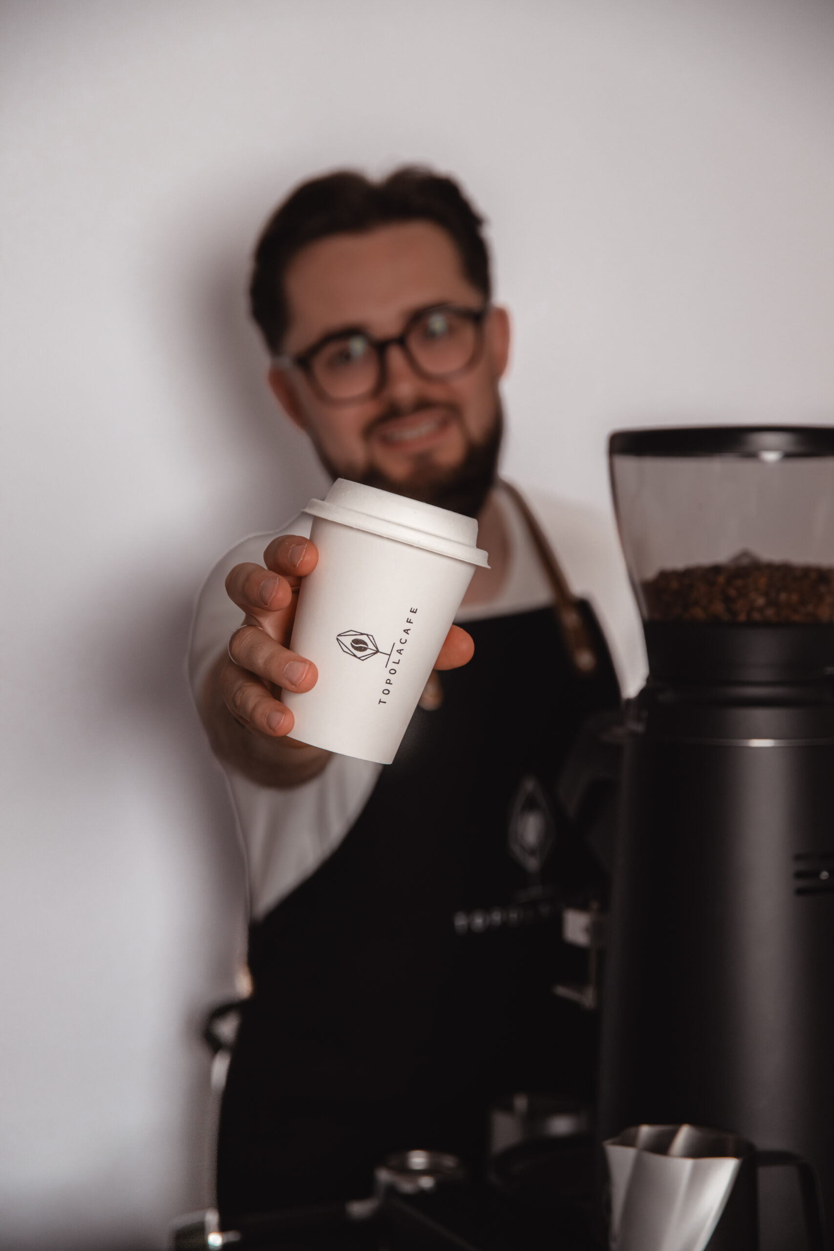 barista topola cafe pokazuje kubeczek kawy na evencie